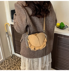 Gros plan d'un sac bandoulière en daim marron en forme de tulipe avec plis sur modèle