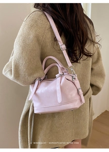 Detailed view of light pink Boston bag worn with a long beige coat for a stylish office look