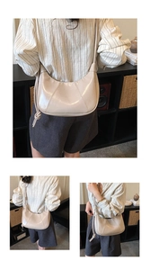Close-up of beige glossy crescent bag showing knot detail and shiny PU leather texture