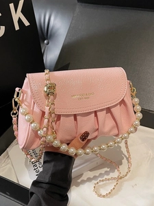 Pink pleated cloud bag for women with gold chain and pearl strap shown in lifestyle view