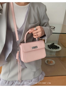 Pink matte leather crossbody bag with silver rotating lock on a minimalist interior background