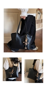 Détail d'un grand sac cabas noir en cuir avec lettrage doré et pendentif lapin mignon