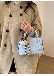 Detail of light blue leather Boston bag with dog charm and brown polka dot bow decoration