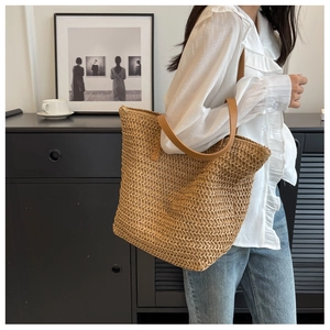 Détail du sac cabas en paille tissée avec anses en cuir marron et fermeture éclair