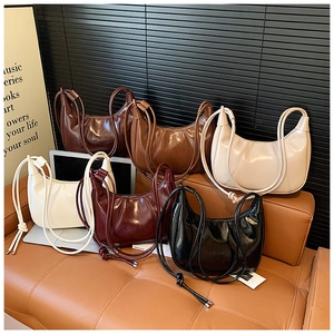 Detailed view of crescent crossbody bags in six colors arranged on a vintage sofa