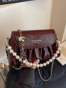 Deep burgundy ruched cloud bag with glossy patent leather, gold chain, and pearl handle