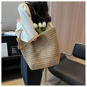 Détail du grand sac cabas en paille tressée avec anses en cuir marron et fleurs