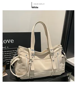 White faux leather tote bag with exterior zipper pockets and long handle in a lifestyle setting