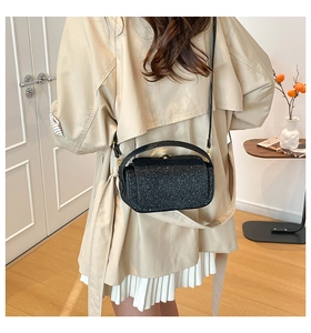 Detail of black glitter crossbody bag paired with elegant beige trench coat and skirt
