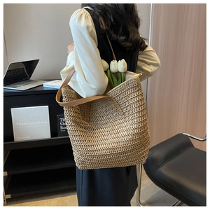 Détail du sac cabas en paille tissée montrant la grande capacité et l'anse en cuir