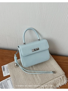Detail of light blue crossbody bag featuring silver heart charm and side knot design