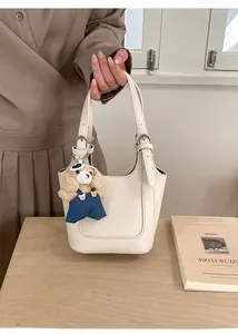 Detail of cream white leather bucket bag with lychee texture and cute bear pendant charm