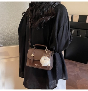 Detail of vintage brown leather crossbody bag with a white plush doll charm