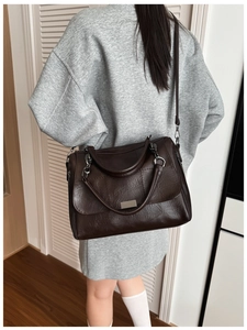 Detailed view of dark brown faux leather shoulder bag with vintage oil wax texture and flap