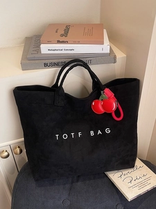Large black tote bag with white text and a red cherry charm on a stylish background