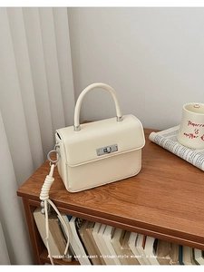 Detail of cream white vintage handbag with silver metal twist lock on a wooden shelf