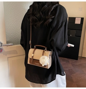 Detailed view of vintage beige crossbody bag with brown leather trim and plush charm
