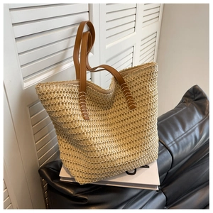 Détail de sac cabas tissé avec anses en cuir marron et coutures blanches décoratives
