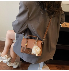 Close-up of caramel retro crossbody bag with lychee texture and plush monster charm