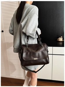 Detail of coffee leather tote bag featuring checkered pattern and gold chain strap