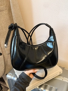 Glossy black crescent moon bag in patent leather with unique knotted shoulder strap