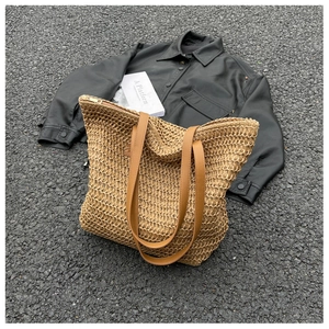 Détail du sac cabas en paille tressée avec anses en cuir marron et texture ajourée