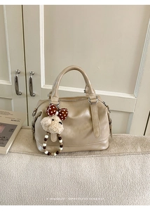 Chic beige Boston handbag with plush bear charm and beaded ring on soft leather