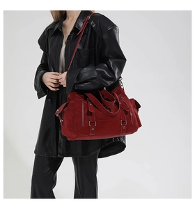 Detail of burgundy large tote bag with decorative straps and silver hardware on leather coat