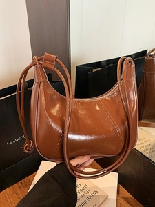 Brown crescent shoulder bag in glossy patent leather with sleek zipper closure and knot detail