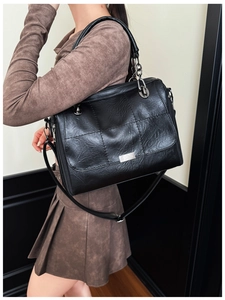Detail of black textured faux leather handbag with silver chain and long shoulder strap