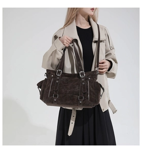 Detail of dark brown leather tote featuring metallic buckles and layered straps