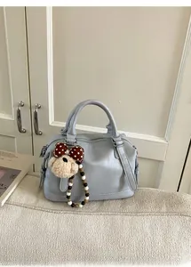 Detail of light blue Boston handbag with silver hardware and a cute teddy bear charm