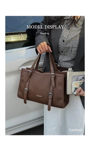 Close-up of brown textured tote bag with vertical stripes and metallic logo detail
