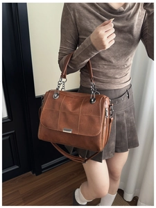 Detail of caramel faux leather shoulder bag with quilted stitching and chain strap