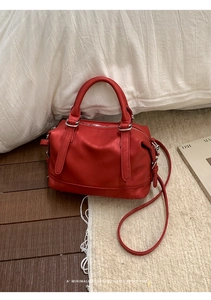 Detail of red Boston bag featuring matte leather texture and silver metal hardware