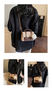 Detail of vintage bicolor crossbody bag with metal accents and plush ball charm