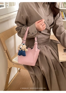 Pink bucket bag with lychee grain leather and cute teddy bear charm in retro setting