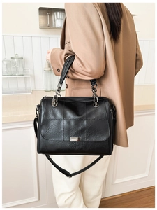 Detail view of black faux leather tote with square stitching and silver chain strap details