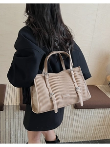 Detail of beige pleated tote bag with vertical strap buckles and dual handles