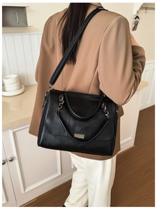 Detailed shot of large black PU leather bag with silver chain and metal plaque accents