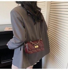Détail du sac matelassé bordeaux avec chaîne dorée porté à l'épaule par un mannequin