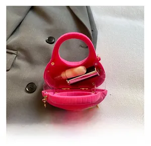 Capacity detail of fuchsia suede mini bag with gold chain and lipstick inside