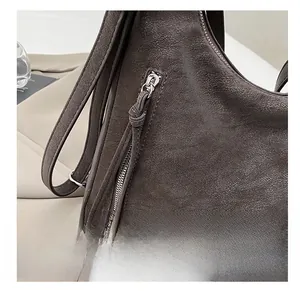 Close-up of smooth metal zipper and lychee pattern leather on dark brown tote bag