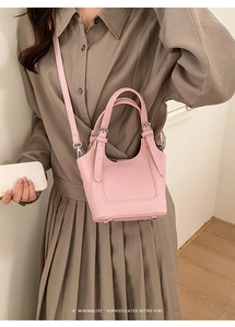 Detail of pink bucket bag with lychee grain texture and minimalist leather top handle
