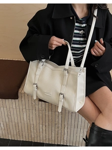 Detail showing the creamy white pleated texture and metal buckles of the tote bag