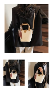 Detail view of cream and brown bucket bag featuring a silk scarf and leather tag