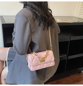 Gros plan détaillé du motif matelassé et de la chaîne dorée sur le sac rose clair