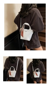 Detail of grey bucket bag with silk scarf on handle and adjustable strap