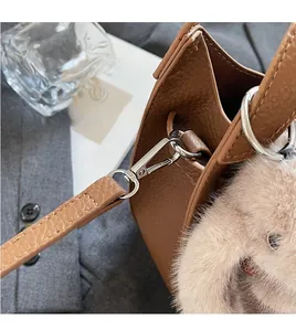 Detail of brown litchi grain leather handbag with silver hardware and plush pendant