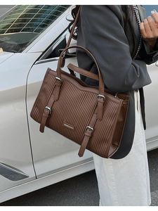 Close-up of deep brown embossed tote bag with silver buckles and a vertical texture